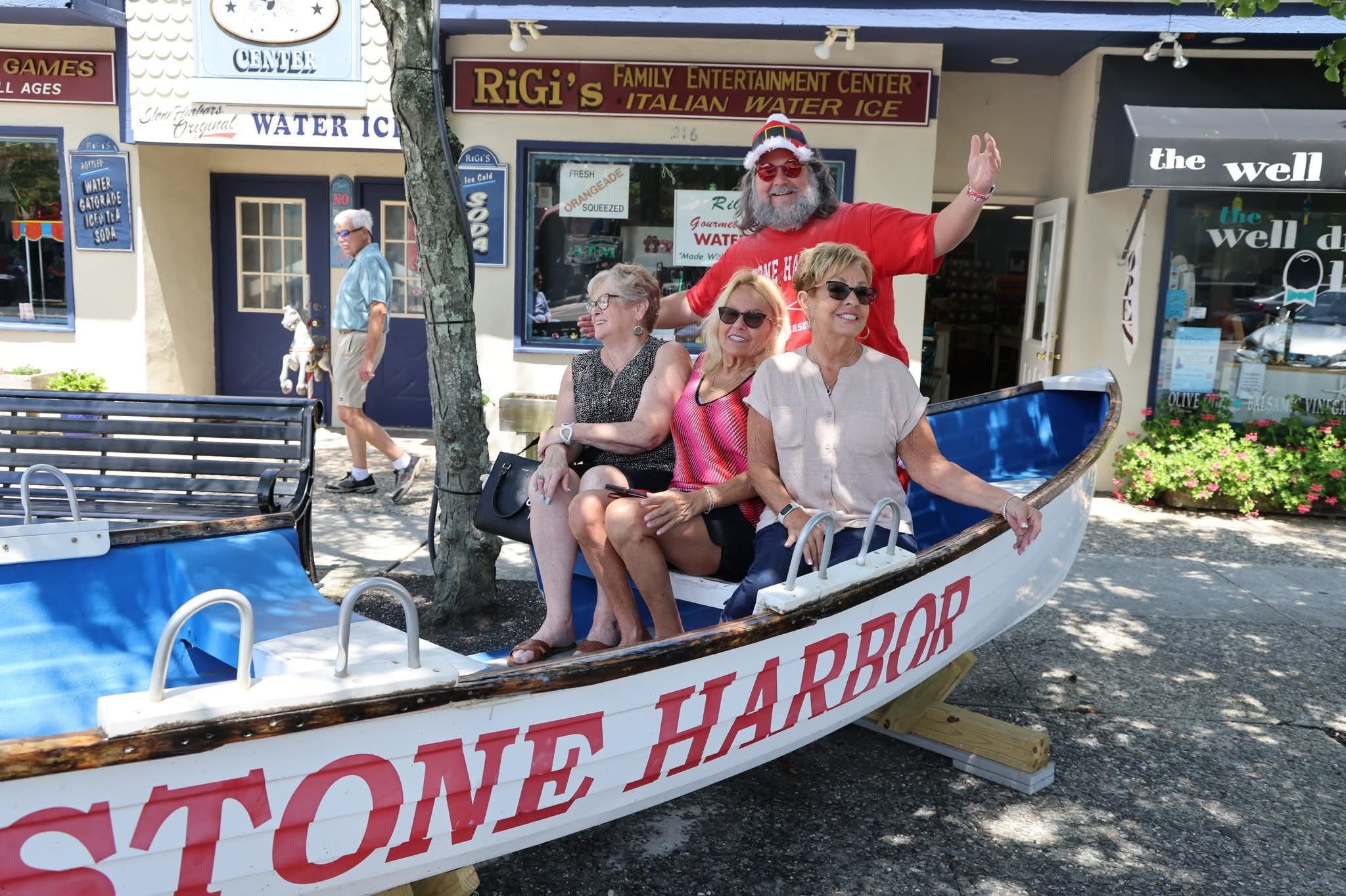 Cape May County Santa waving with arms wide open behind three women in the Stone Harbor boat