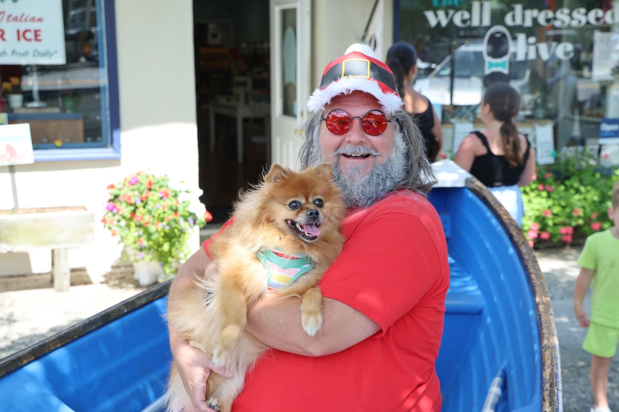 Cape May County Santa holding a Pomeranian in a rainbow harness in the Stone Harbor boat