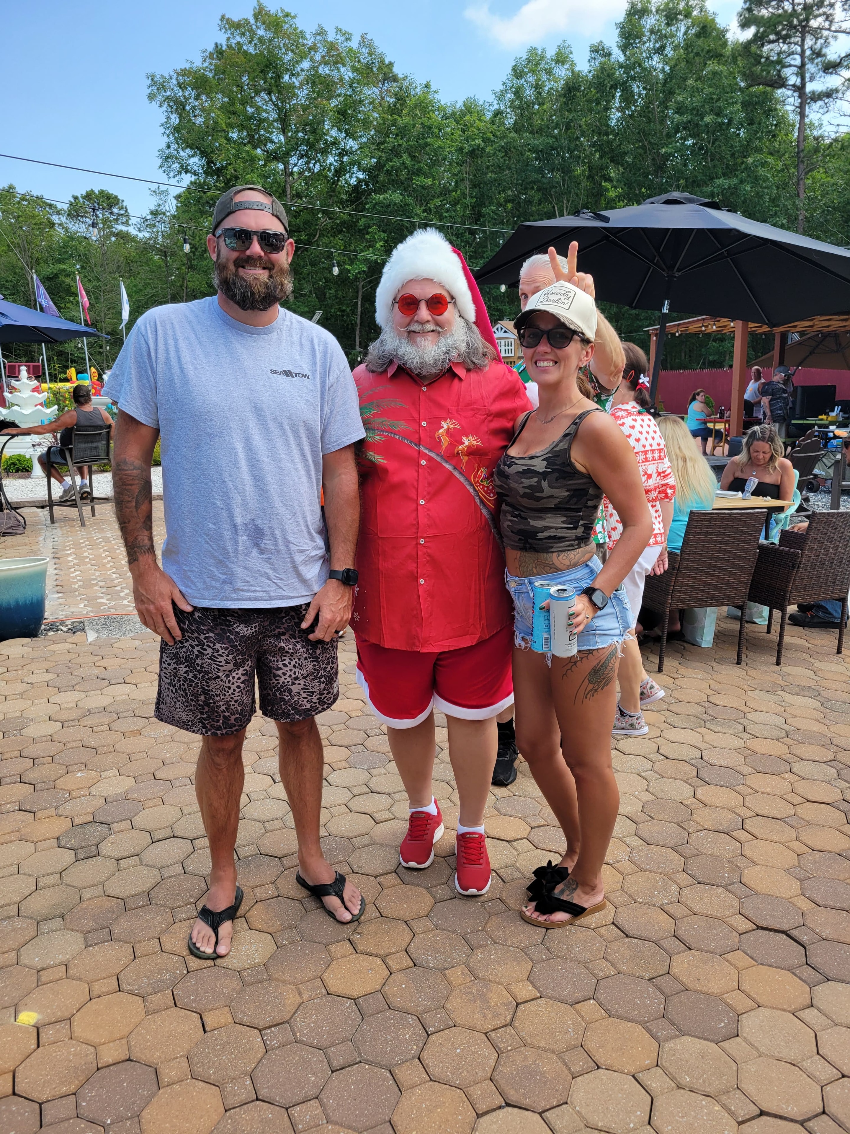 Cape May County Santa in Hawaiian shirt posing with a couple at an outdoor patio