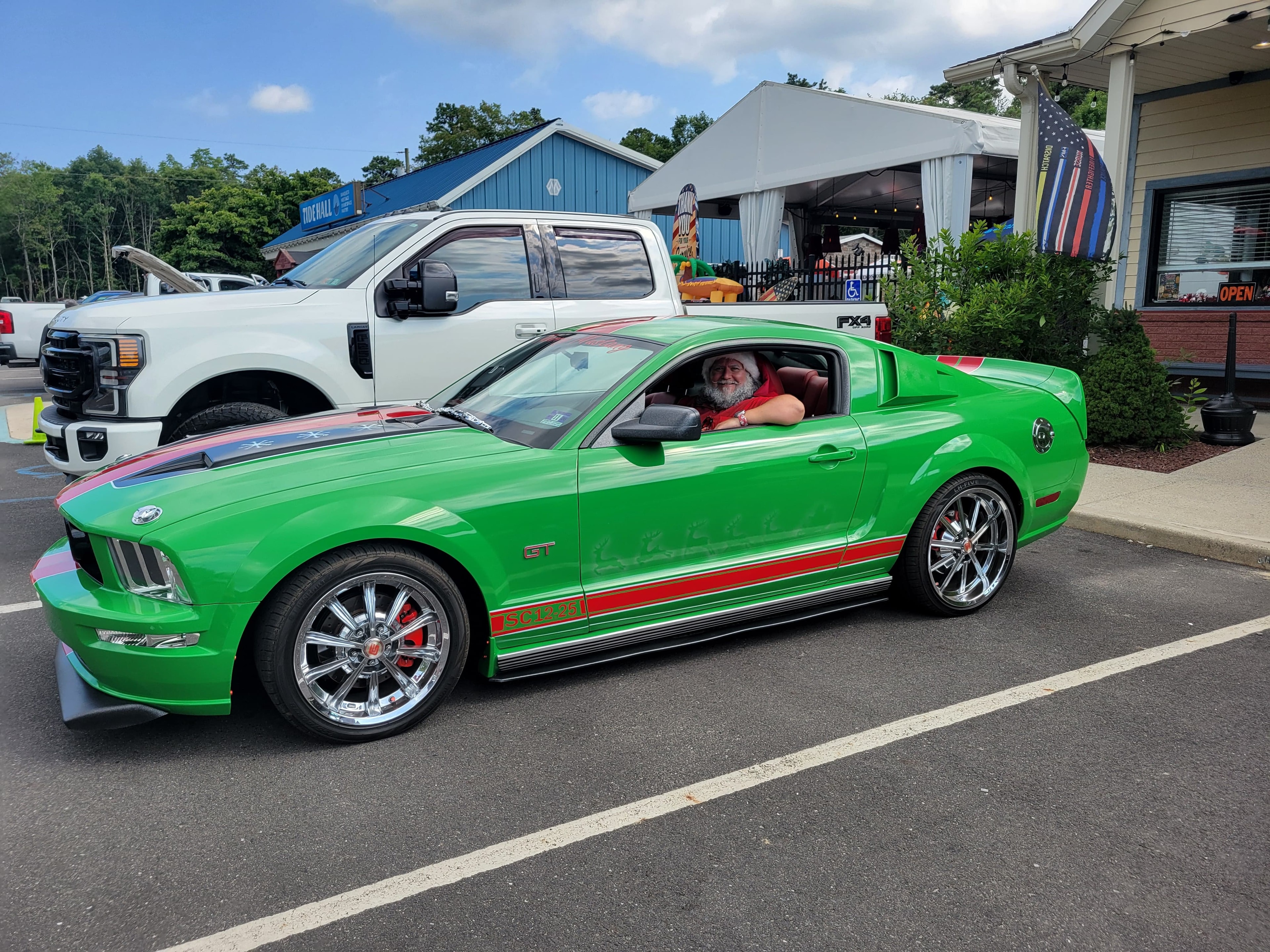 Cape May County Santa sitting in the driver seat of a green Christmas-themed Ford Mustang GT at a car show