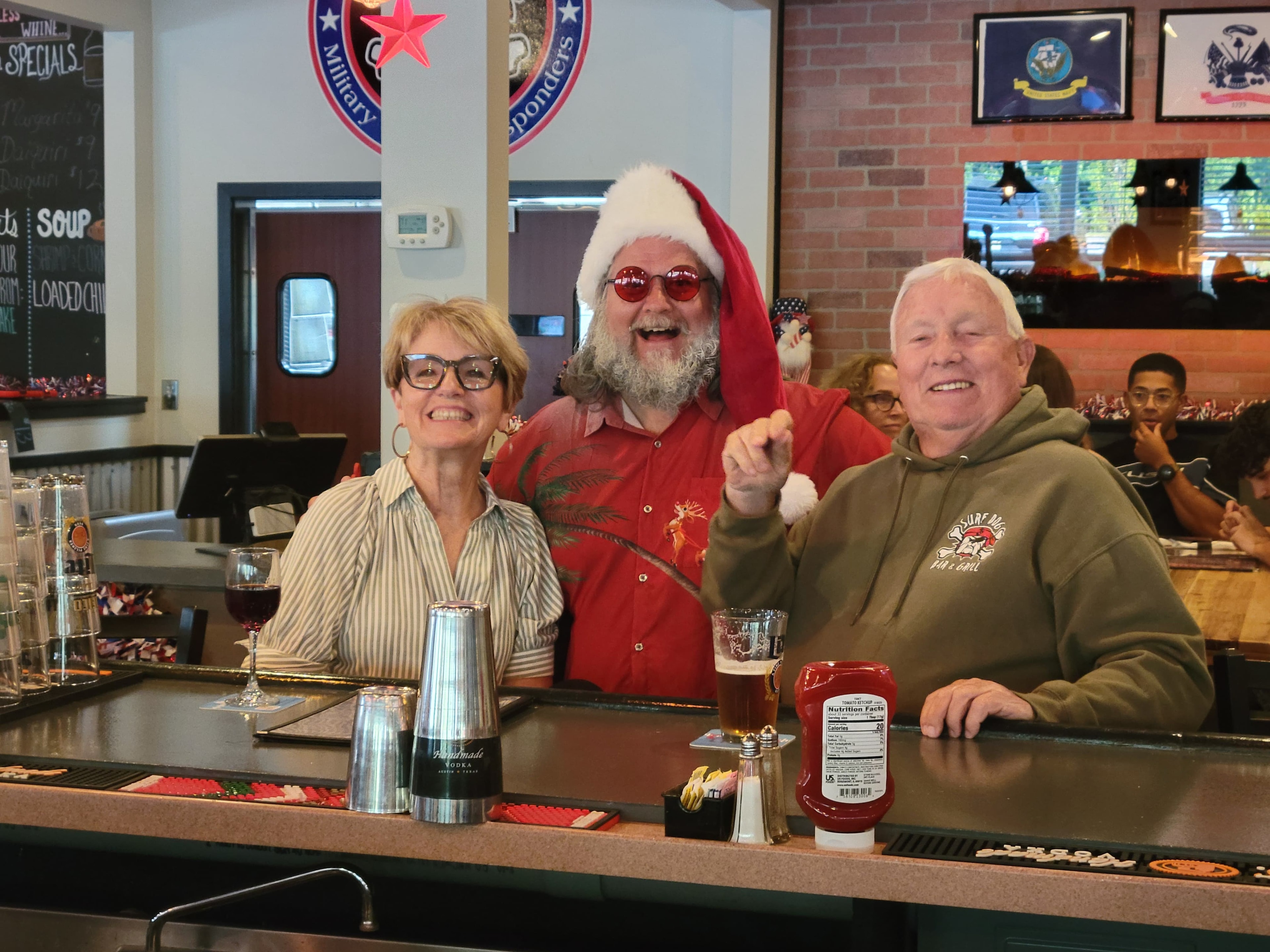 Cape May County Santa laughing with a couple at the bar inside Surf Dog Bar and Grill