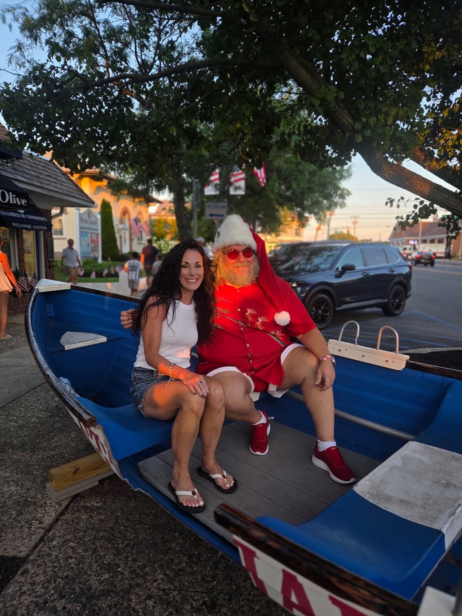 Cape May County Santa sitting in a blue boat on the Stone Harbor street with a woman at sunset