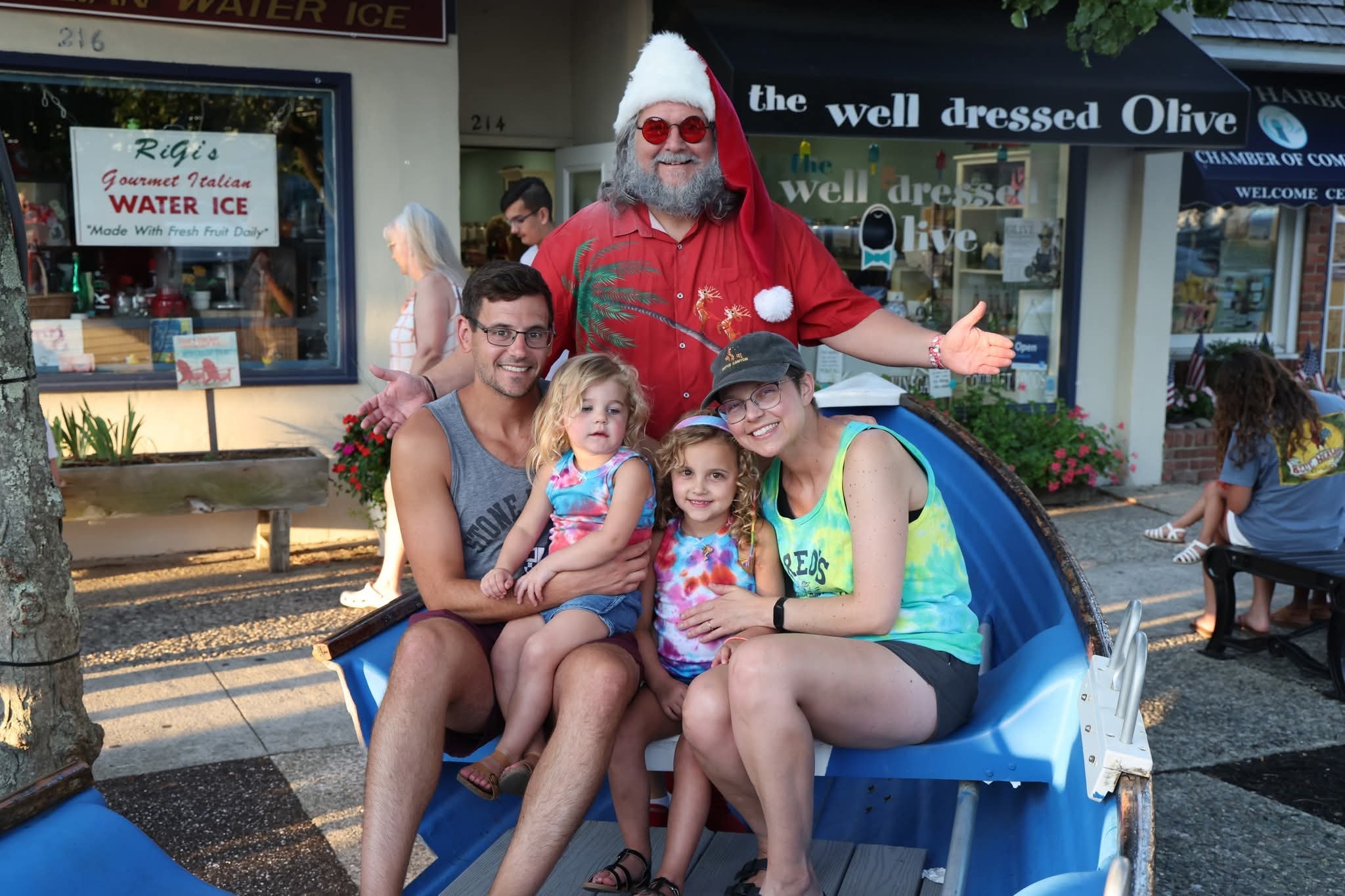 Cape May County Santa with arms wide open behind a dad, two toddlers in tie-dye, and a mom in the Stone Harbor boat