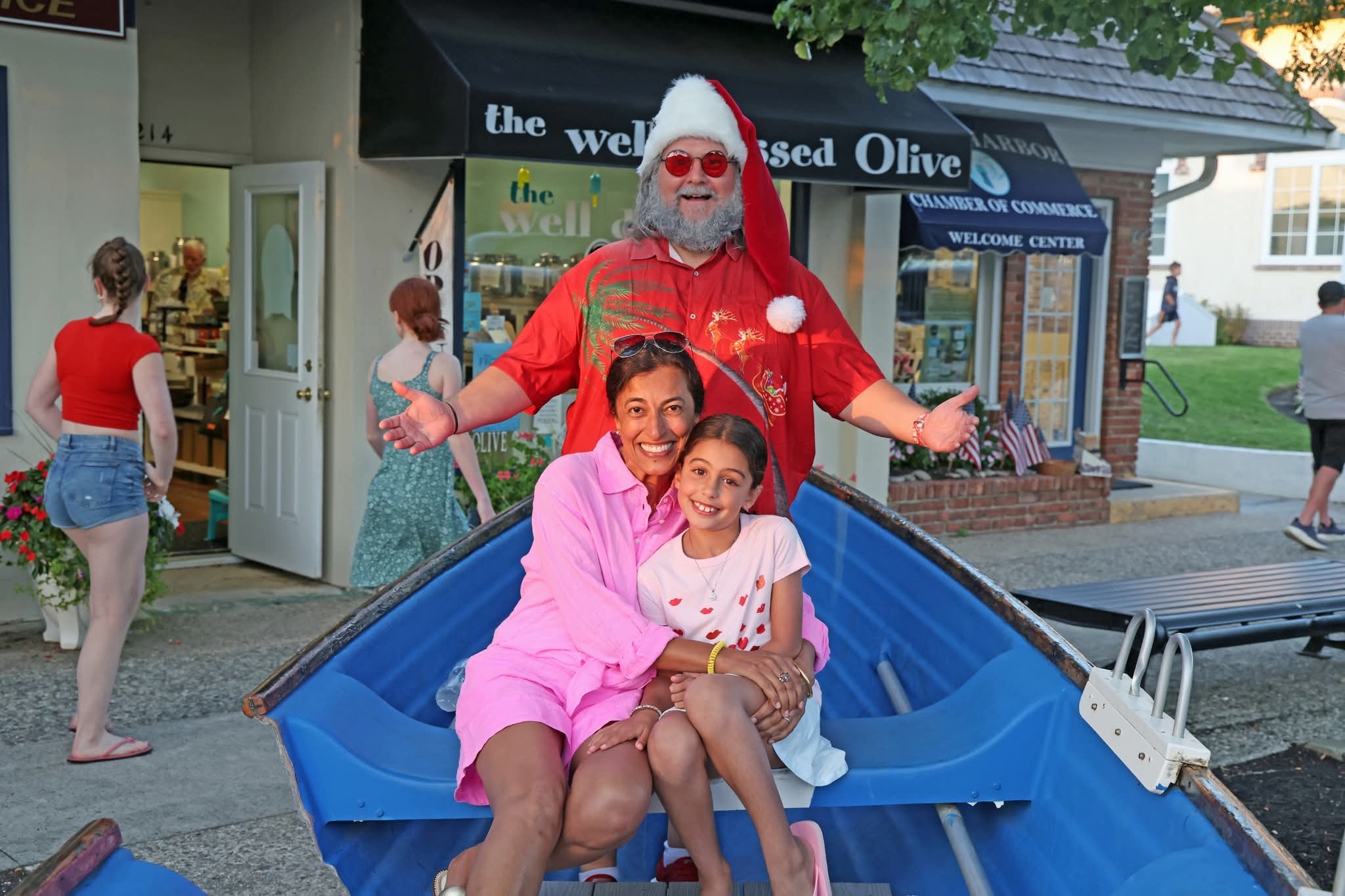 Cape May County Santa with arms wide open behind a mom and daughter in the Stone Harbor boat