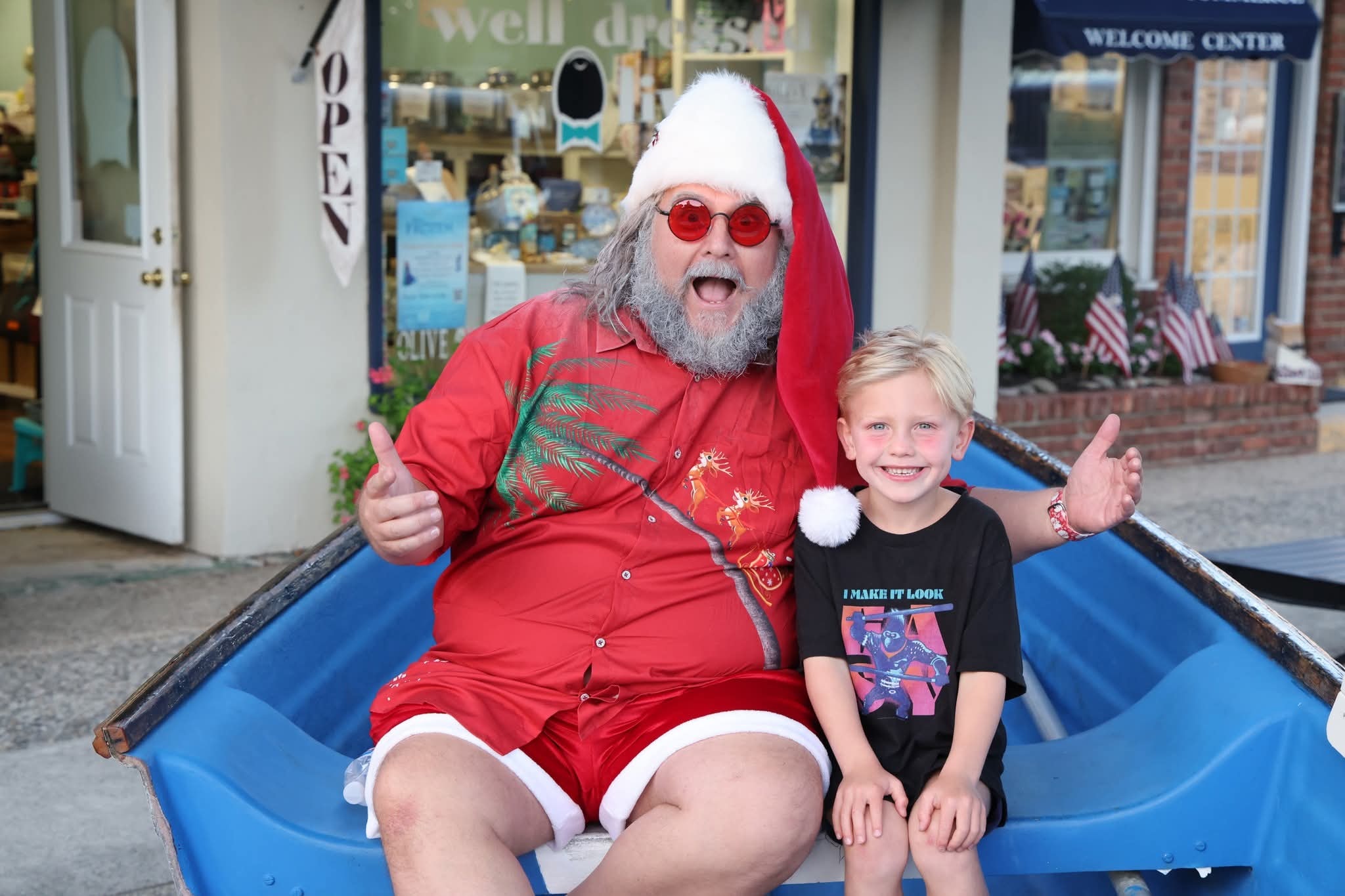 Cape May County Santa with double thumbs up next to a boy in an I Make It Look Easy shirt in the Stone Harbor boat