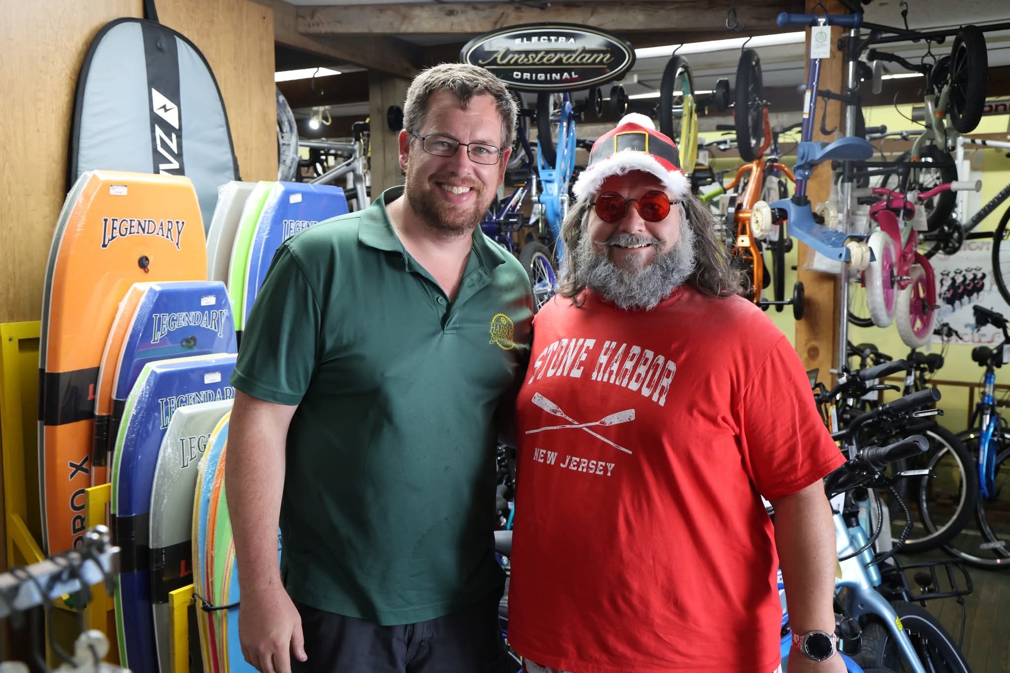 Cape May County Santa with a man at Harry's Bike Shop surrounded by bikes and boogie boards