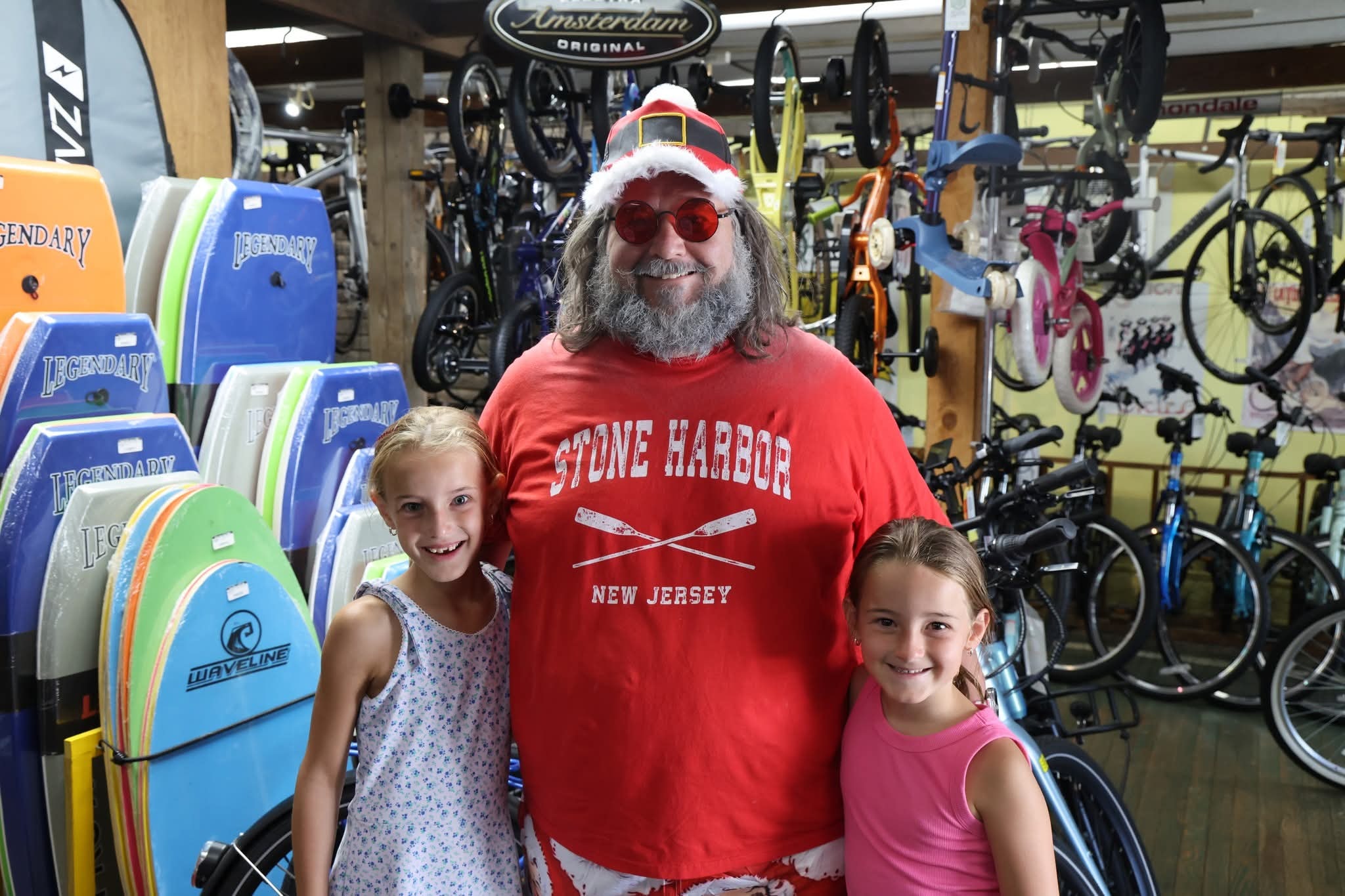Cape May County Santa with two young girls inside Harry's Bike Shop surrounded by boogie boards and bicycles