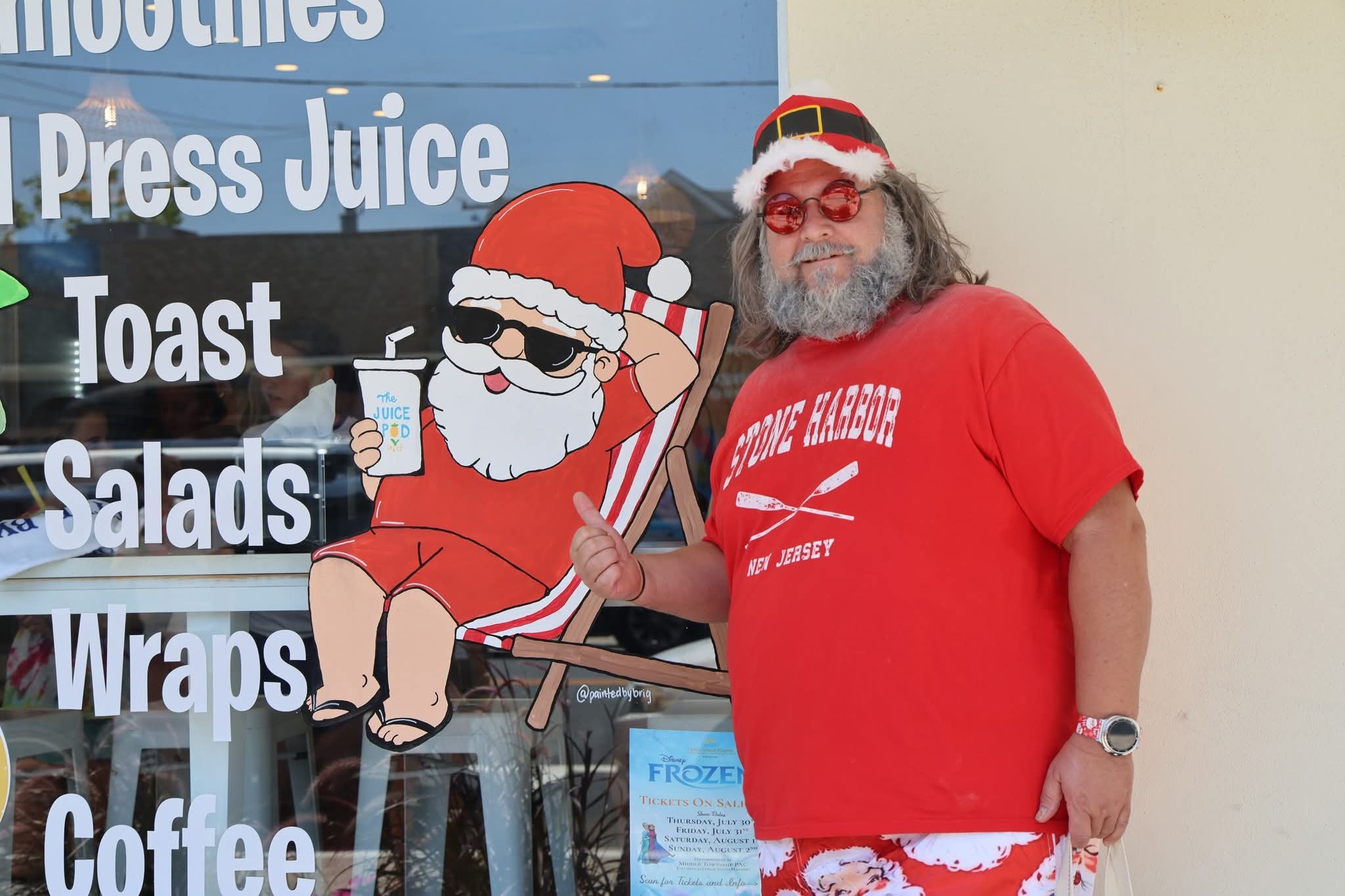 Cape May County Santa posing next to the Juice Pod window Santa illustration with thumbs up